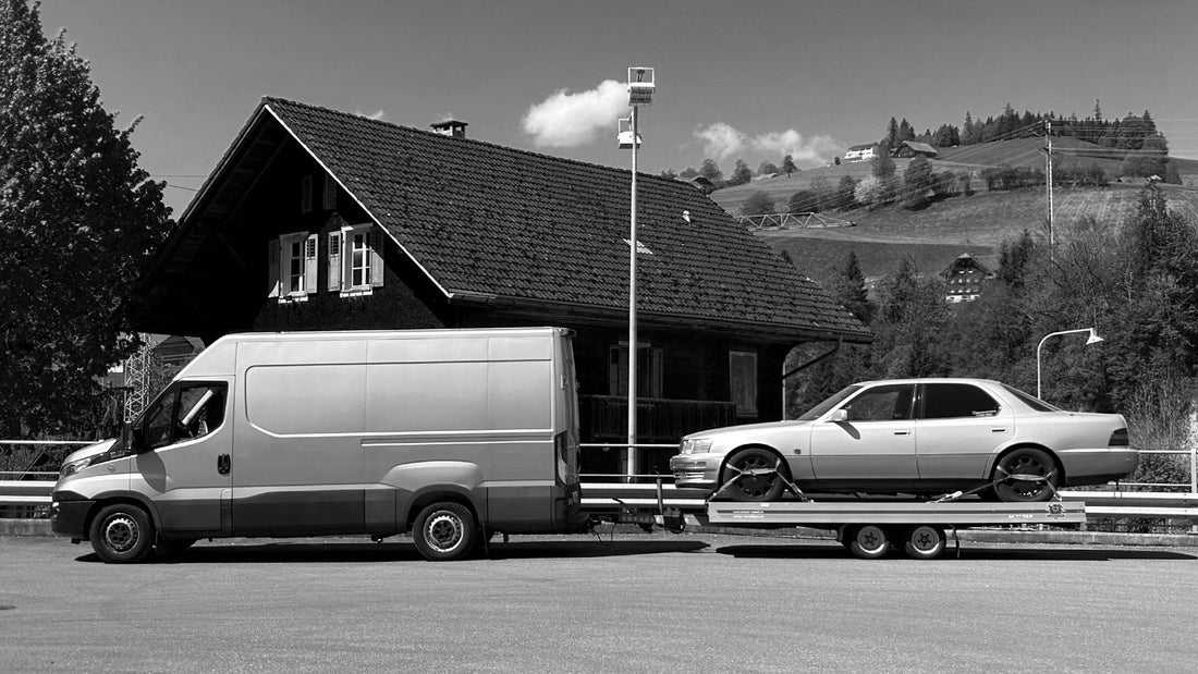 Transporter mit Autotransport-Anhänger und beladenem Youngtimer vor Schweizer Bergkulisse. MediaMechs Entlebuch